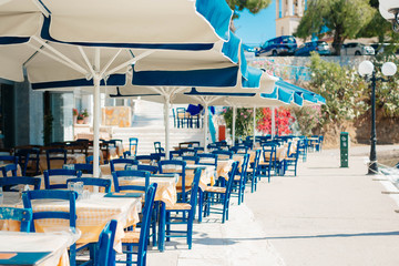 Romantic  restaurant with blue chairs and tables under palm leaves