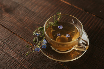 glass cup of tea with herbs. flowers in the cup.