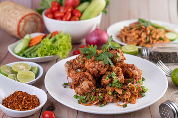 Spicy minced chicken on a white plate complete with cucumber, lettuce and side dishes.