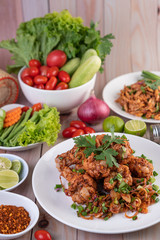 Spicy minced chicken on a white plate complete with cucumber, lettuce and side dishes.