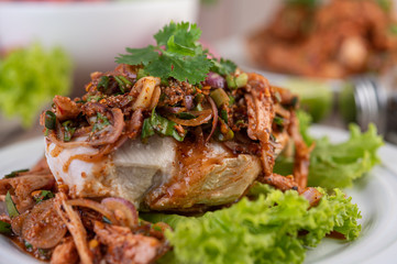 Spicy minced chicken on a white plate complete with cucumber, lettuce and side dishes.