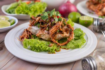 Spicy minced chicken on a white plate complete with cucumber, lettuce and side dishes.