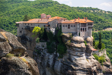 old monastery on a sheer mountain, a house for monks with orange roof tiles, a stone building on a...
