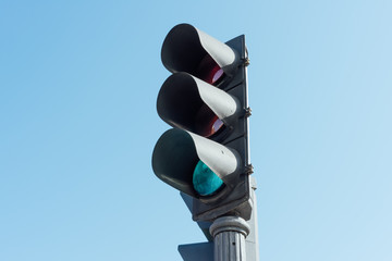 old traffic light in green with blue background