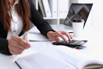 Businesswoman in the office keeps her hand on the calculator