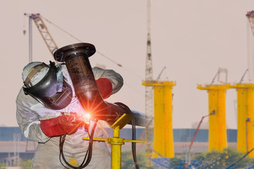 A young man welder in brow uniform, welding mask and welders leathers, weld metal with Tig, arc...