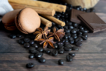 detail of coffee beans, cinnamon stick, star anise, chocolate and coffee macarons on wooden table