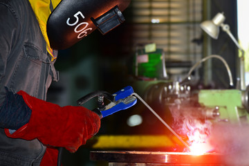 welder in Industrial worker with welding tool with sparks light weld and smokes in factory.