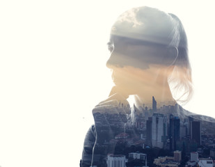Double exposure portrait of a woman in contemplation at sunset time above the city