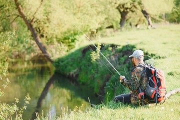 young fisherman fishes near the river. The concept of outdoor activities and fishing