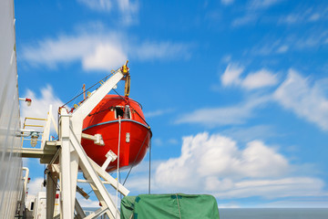Ship lifesaving equipment, lifeboat with copy space on blue sky.