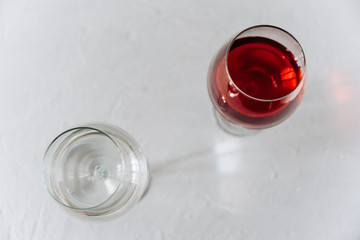 two wine glasses on a grey background one with red wine and the other with water