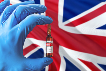 United Kingdom flag with Coronavirus Covid-19 concept. Doctor with blue protection medical gloves holding a vaccine bottle. Epidemic Virus, Cov-19, Corona virus outbreaking.