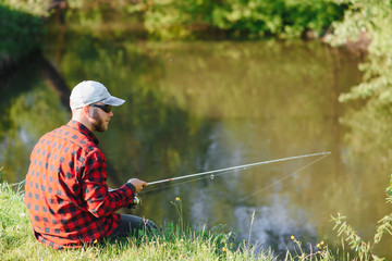 young fisherman fishes near the river. The concept of outdoor activities and fishing