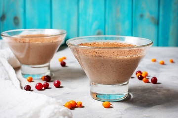 Two glasses of cheese-chocolate mousse with berries on concrete background