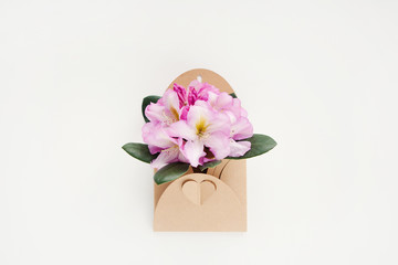 Bouquet of spring flowers in craft envelope with heart on white background. International Mother's day, Father's day, Valentine day, birthday, eco concept. Minimalism