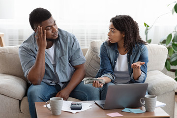 Couple accounting family budget at home, wife scolding husband for overspending
