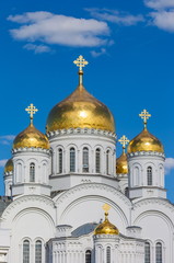 Fototapeta na wymiar Gilded dome of the Orthodox Church against the blue sky with clouds in summer closeup