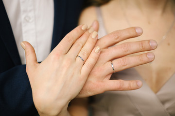The joined hands of the bride and groom at a wedding. Wedding rings on the fingers of the newlyweds. Hands close up. 