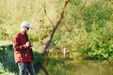 Fisher man fishing with spinning rod on a river bank, spin fishing, prey fishing