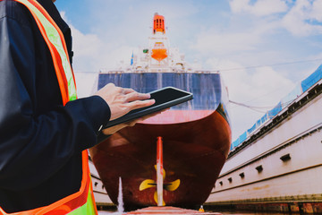 Workers with an Tablet in hands on a floating dock at the Stern propeller and a shafting port...