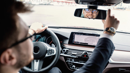 Young businessman driving alone adjusting rear view mirror