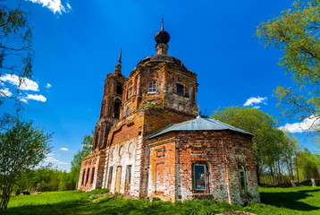 Abandoned Orthodox Church in summer against the blue sky and white clouds