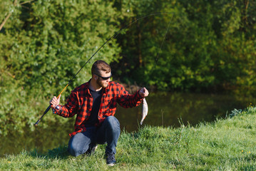 Fisher man fishing with spinning rod on a river bank, spin fishing, prey fishing