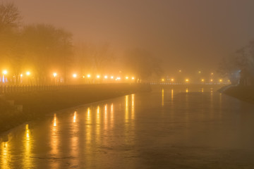 Fototapeta na wymiar Night landscape with fog and lanterns on the banks of a frozen river in Strelka Kharkiv square