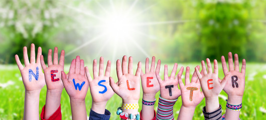 Children Hands Building Colorful English Word Newsletter. Sunny Green Grass Meadow As Background