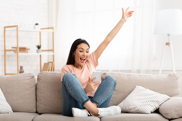Girl celebrating victory online using cell phone