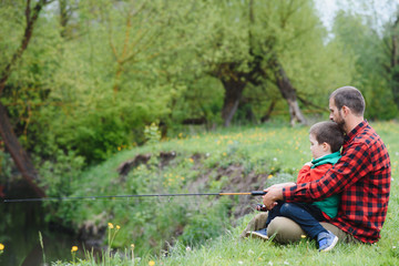 Naklejka na ściany i meble Dad and son fishing outdoors. father's day