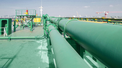 On Deck of chemical tanker ship with pipe line connection while the ship is at sea green pipe line...