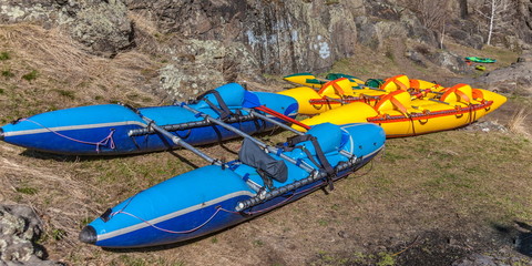 Colorful catamarans for rafting on the river on the background of rocky rock and land in the spring
