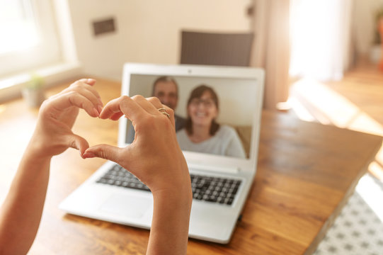 Video Chat With A Parents. Female Hands Are Showing Heart Shape To Parents On The Laptop Screen. Video Call, Love Sign