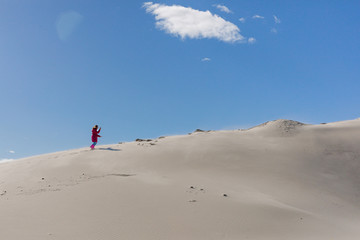 A teenager is  going up to sandy stack against a clear blue sky. The stack grit,  sandy mound. Concept of difficult way to the destiny.