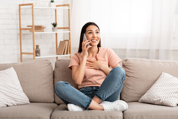 Obraz premium Excited woman talking on mobile phone sitting on couch