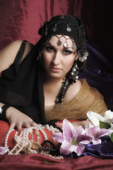 eastern woman in black clothes lies on pillows