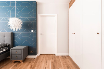 White, blue and grey design of stylish bedroom interior with closed door