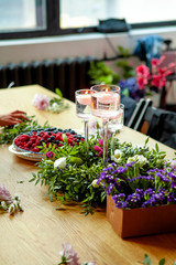 preparation for a master class in floristry. Table decor elements (wreath of fresh plants and citruses, burning candles)