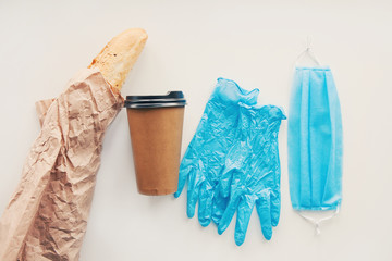 Medical gloves, mask, baguette in paper packaging on white background. Online shopping, delivery service, disease outbreak, coronavirus covid-19 pandemic situation
