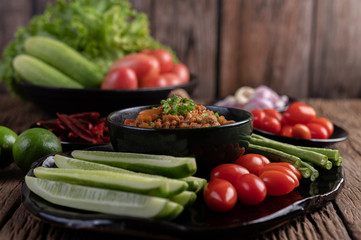 Sweet pork in a black bowl, complete with cucumbers, long beans, tomatoes, and side dishes