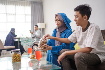 boy and girl enjoying snacks on eid mubarak celebration with family at home. hari raya idul fitri tradition