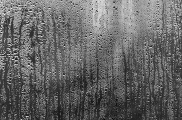 The traces of rain on the glass. The view through the mesh. Black and white