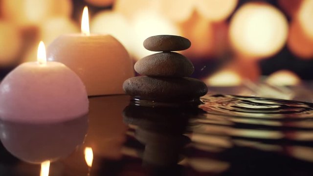spa or health club, dropping a pure water drop from a leaf. background bokeh of blurred burning candles scented environment. Concept: relaxation, wellness, body care, spa, nature 