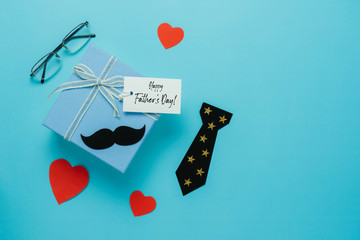 Table top view Happy Fathers day holiday background concept.Flat lay  gift  box for dad with accessories objects sign of season the wallet,Gift box & love heart and greeting card on blue paper.