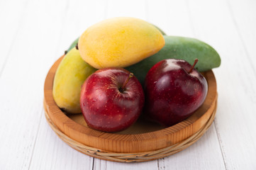 Naklejka na ściany i meble Apples and mangoes in a wooden tray.