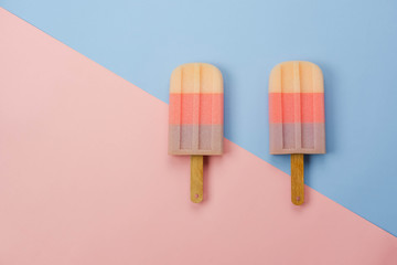 Table top view aerial image of sign or food of summer season holiday background concept.Flat lay of pastel sweet ice cream on modern rustic pink paper backdrop.Minimalism and copy space design word.