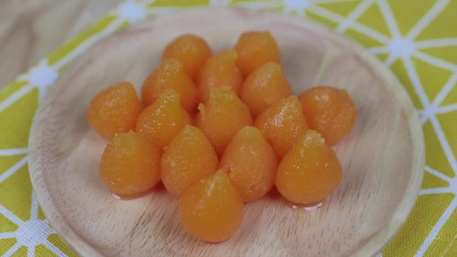 A kind of Thai Sweetmeats - Thong Yot on a wooden plate . Golden Drops , Eggdrop Sweet , Golden Balls , Thai famous desserts , rotating on a wooden plate
