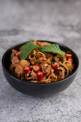 Spicy pork chops in a black cup consisting of lemons and chilies